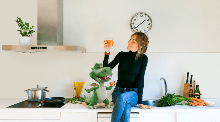 Female sitting on kitchen bench drinking a glass of juice with the St.George Little Dragon